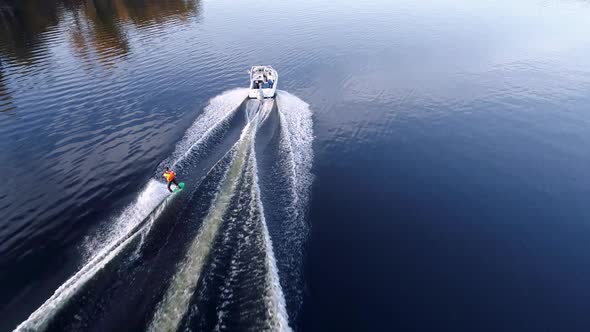 Wake Boarding. Motor Boat Pulls a Surfer Riding the Water Surface on His Board. Aerial View