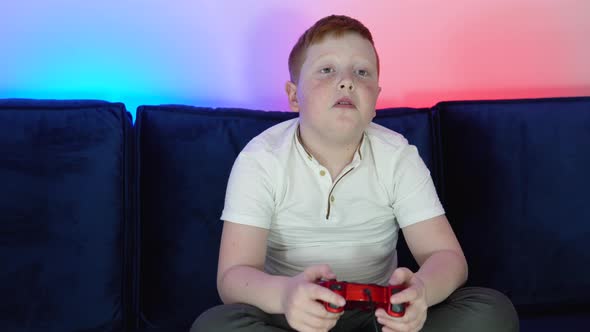 Excited Little Boy Gamer is Sitting on a Couch Playing and Winning in Video Games on Console