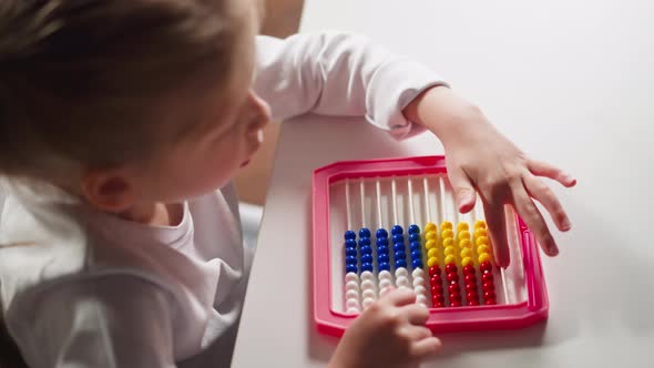 Little Schoolgirl Does Sums Moving Plastic Beads on Abacus