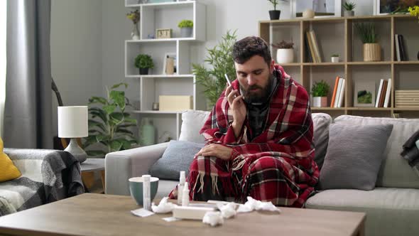 Ill Man Uses a Smartphone at Home on the Sofa