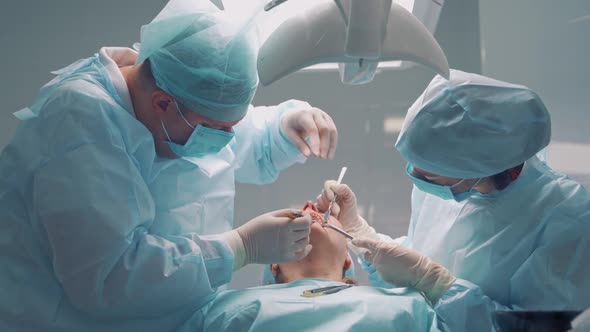 Dentist male works with a thread in patient's mouth in dental clinic