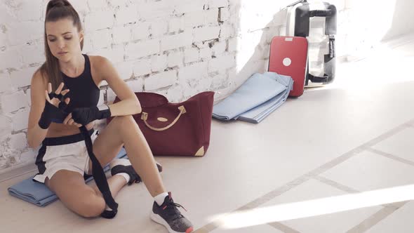 A Pretty Young Athlete Wraps a Boxing Bandage Around Her Arm Before Training