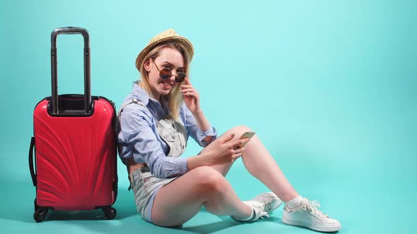 Girl in Sunglasses and Hat Posing in Studio on Blue Background.