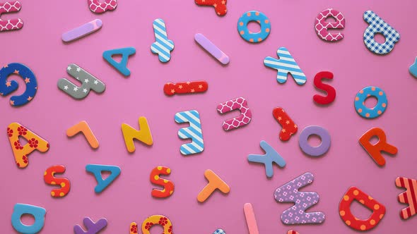 Colorful Magnetic, Plastic and Paper Alphabet Letters Placed Randomly on Pink Background