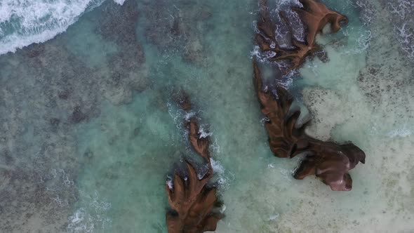 Aerial view from above of clear water crashing on rocks La Digue Seychelles