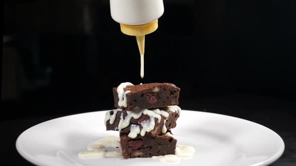 Pouring Icing on Brownies Dessert. Slow Motion. Making Dessert in Coffee House. Stack of Brownies