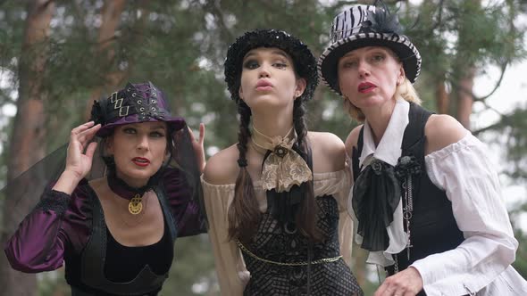 Three Concentrated Women Looking at Camera Posing in Steampunk Halloween Costumes Outdoors in Forest