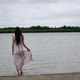 Dressed young woman is entering in the lake in windy day - VideoHive Item for Sale
