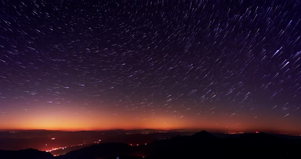 The stars are spinning in the starry night sky over the mountains, startrails 4K