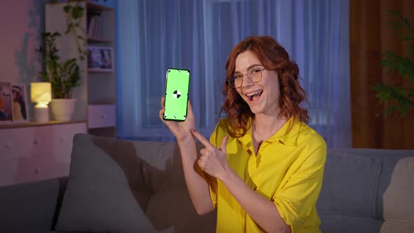 Girl in Glasses Shows Finger to Screen of Mobile Phone with Green Chroma Key While Relaxing at Home