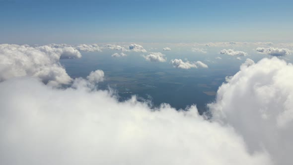 Aerial View From Airplane Window at High Altitude of Earth Covered with White Puffy Cumulus Clouds