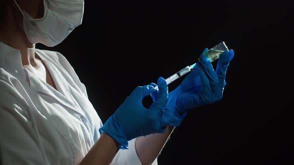 Doctor Filling Syringe with Solution on Black Background