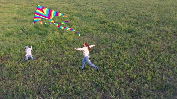 The Mother and Boy Run with a Kite on a Green Field