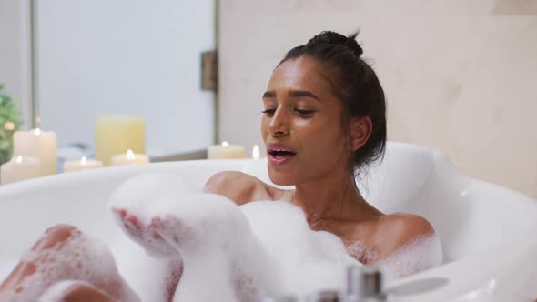 Mixed race woman lying in a bathtub at home