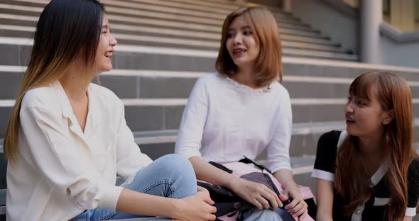 Group of Asian girl friends meeting and talking on stairway front of the building.