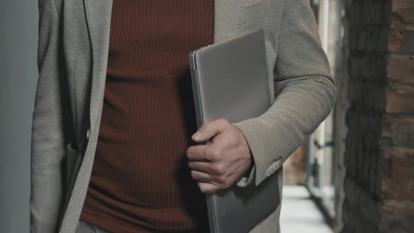 Mid-Section of Businessman with Laptop Walking through Office