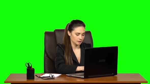 Girl Enthusiastically Works Behind a Laptop, Smiles and Enjoys the Result. Green Screen