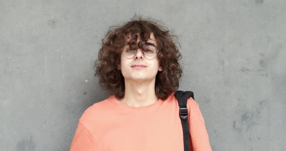 Portrait of Caucasian Teenage Boy with Glasses and Long Hair Looking at Camera