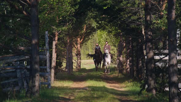 Two People are Riding Horses Through the Forest