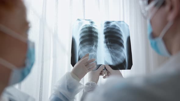 Back View Closeup of Male and Female Doctors in Covid Face Masks Examining Lungs Xray