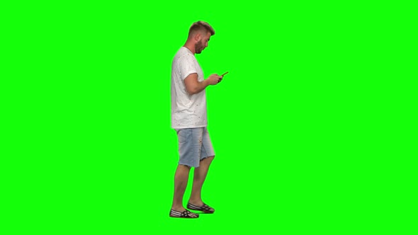 Bearded Guy Calmly Walking and Texting Message Vie Her Mobile Phone on Green Screen. Chroma Key