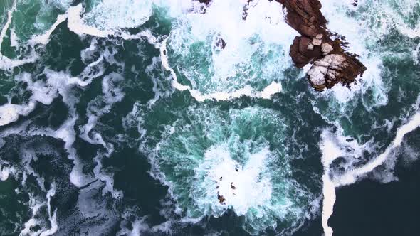 Aerial - Top down shot of turbulent ocean thrashing rocky coastline, Hermanus South Africa