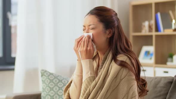 Sick Woman Blowing Nose in Paper Tissue at Home