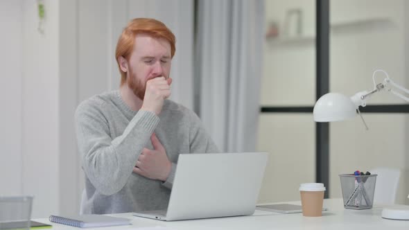 Redhead Man Coughing While Working on Laptop