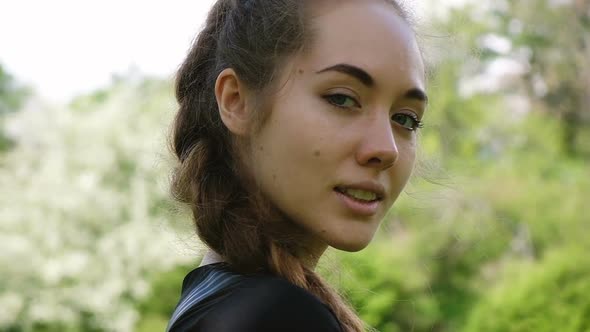 Portrait of a Sexy Woman with a Long Braid in Nature. Attractive Girl Winks at the Camera