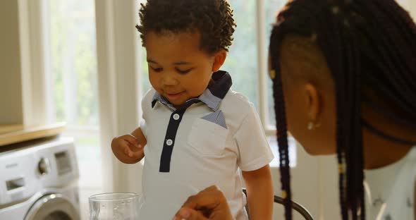 Close-up of young black mother and son sitting at dining table in kitchen of comfortable home 4k