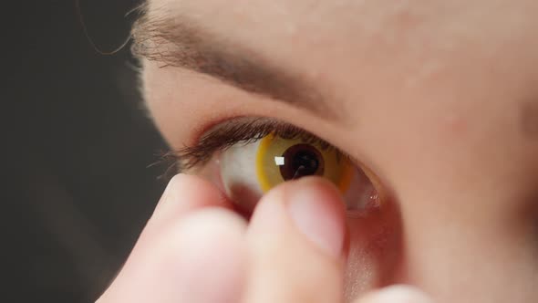 Closeup of Brown Eye Young Woman Taking Off Yellow Lens