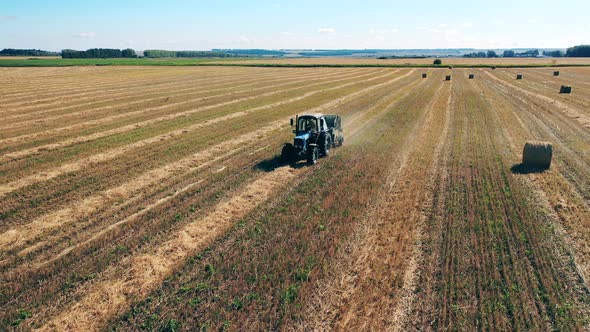 Field with a Tractor and Multiple Piles of Hay