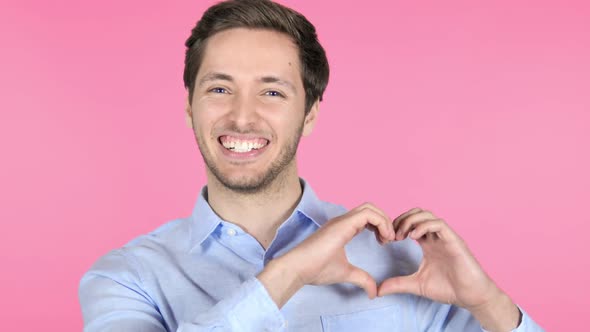 Handmade Heart By Young Man Isolated on Pink Background