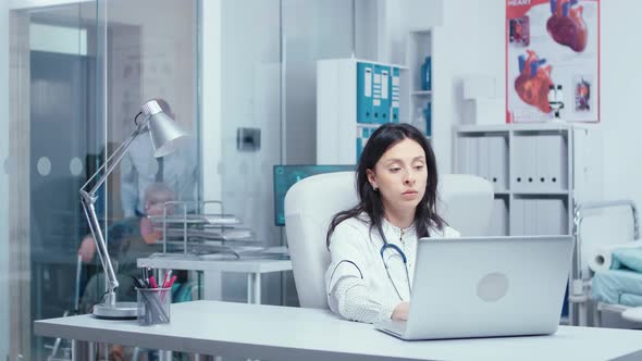 Young Woman Doctor Typing on Laptop