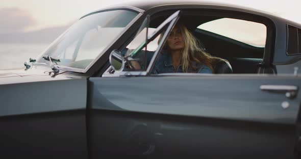 Beautiful woman in a vintage car at sunset