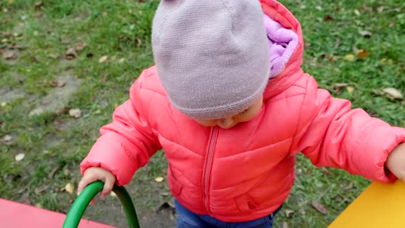 Cheerful toddler girl playing at children playground. Slow motion.