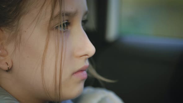 Sad Little Girl in the Car Looking Out the Window