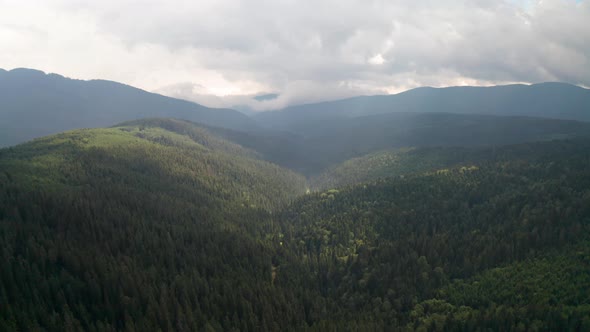 Drone flight above green tree-covered mountain slopes