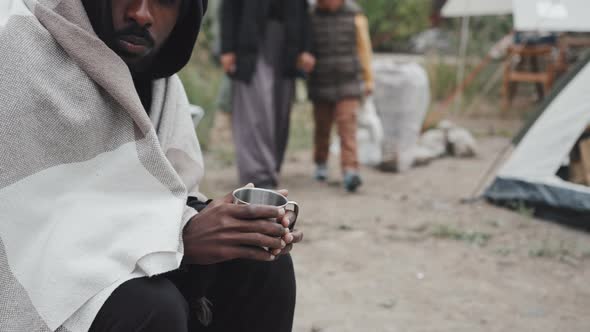 Homeless Black Man Drinking Hot Tea at Refugee Camp