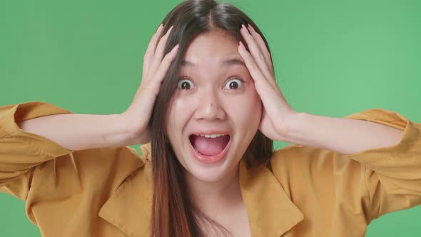 The Shocked Asian Woman Grabbing Her Head While Saying Wow On Green Screen Background In The Studio