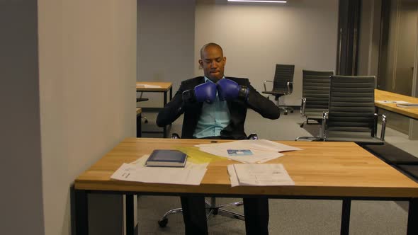 AfroAmerican Businessman Sitting with Boxing Gloves in Office