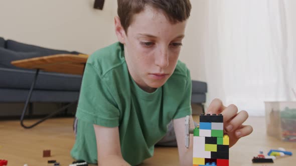 Young boy playing and constructing with toy bricks on the living room floor