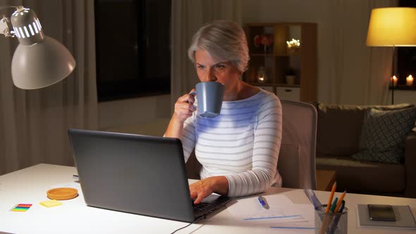 Senior Woman with Laptop Drinking Coffee at Home