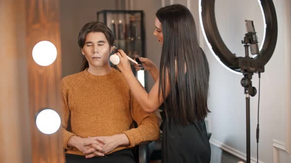 Woman Make Up Artist Applying Cream Contour on the Face of an Asian Male Model Using a Brush