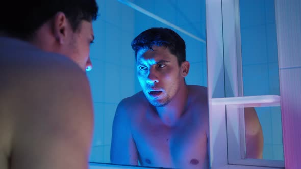 Tired Man with Stubble on His Face Washes in Bathroom and Look Himself in Mirror