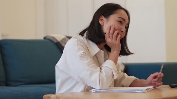 Pensive Asian woman writing something