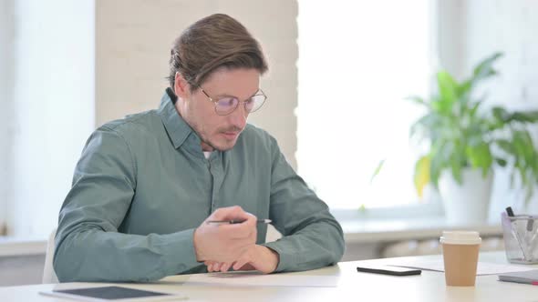 Pensive Middle Aged Man Writing on Paper Thinking