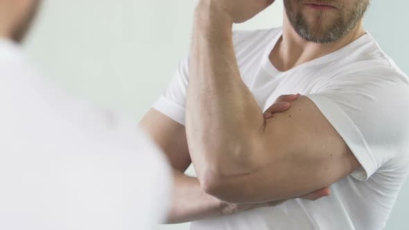 Attractive Man in White T-Shirt Admiring Himself, Showing Biceps, Close-Up