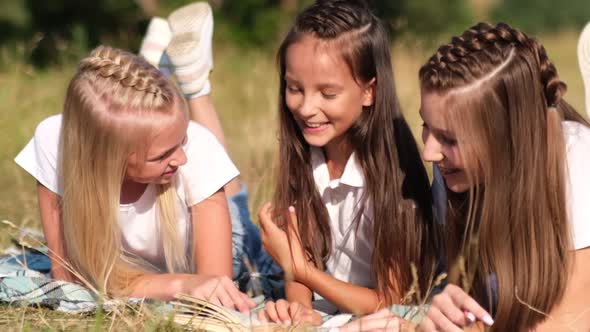 Three Happy Girls Lying on Blankets and Reading Books Spending a Day in the Park