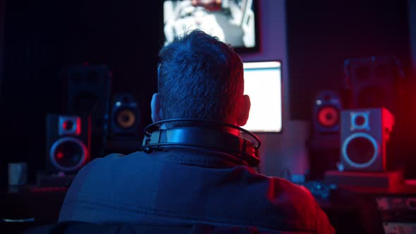 A Man Sound Engineer in Headphones Recording Audio Tracks for a Young Man Rapper - Working in the